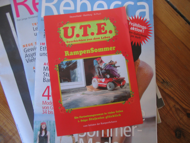 Ein Flyer im Design eines "Groschenromans" mit dem Titel "U.T.E. | Rampensommer" liegt auf einem Stapel Rebecca-Zeitschriften