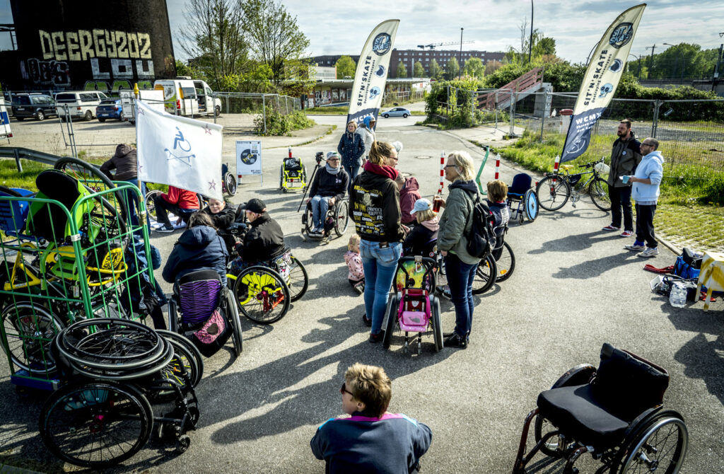 Eine Gruppe von Menschen mit und ohne Rollstuhl steht im Startbereich des UTE-Tandem-Cups